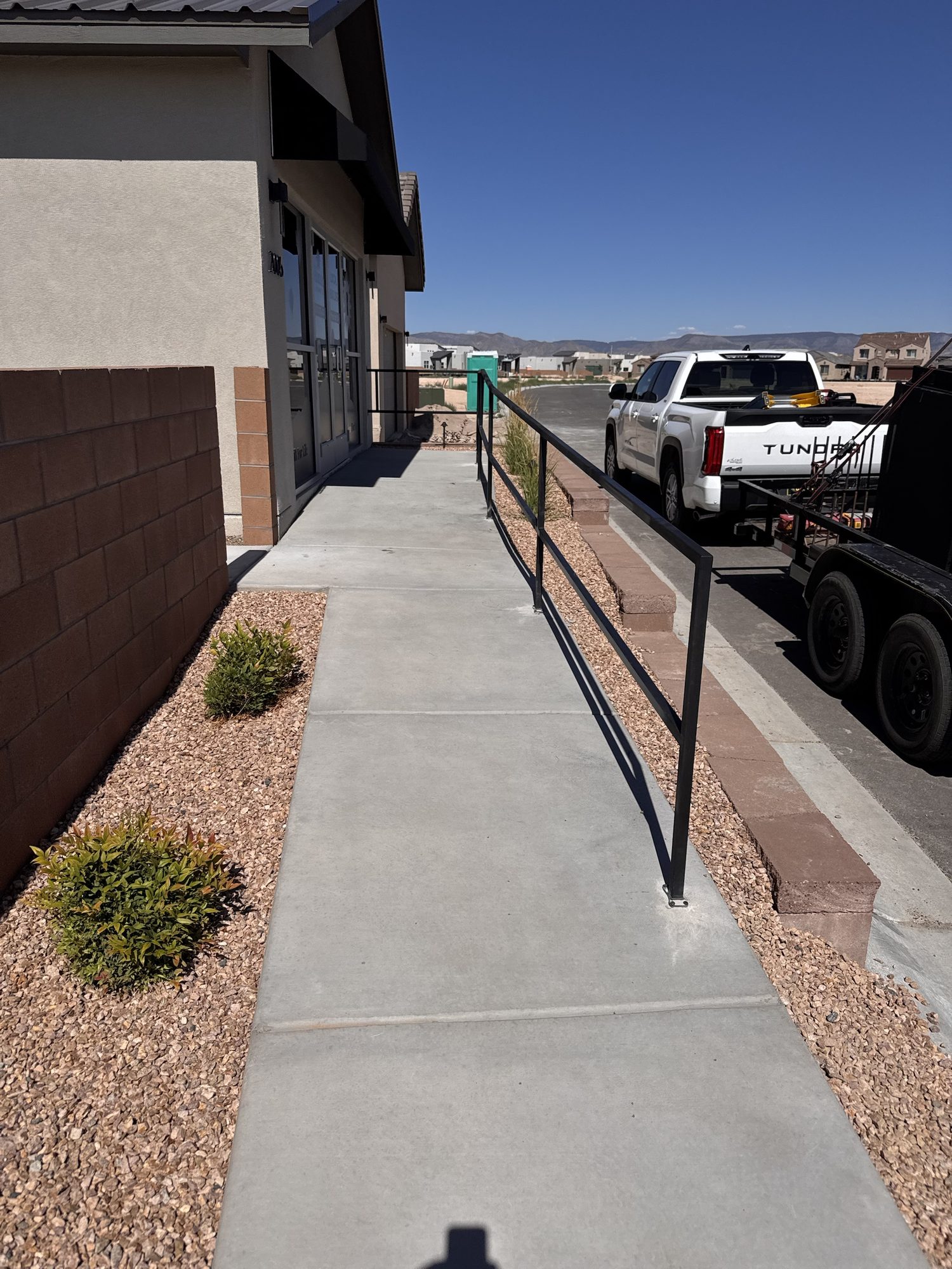 Steel handrail fabricated to follow a concrete access ramp and walkway