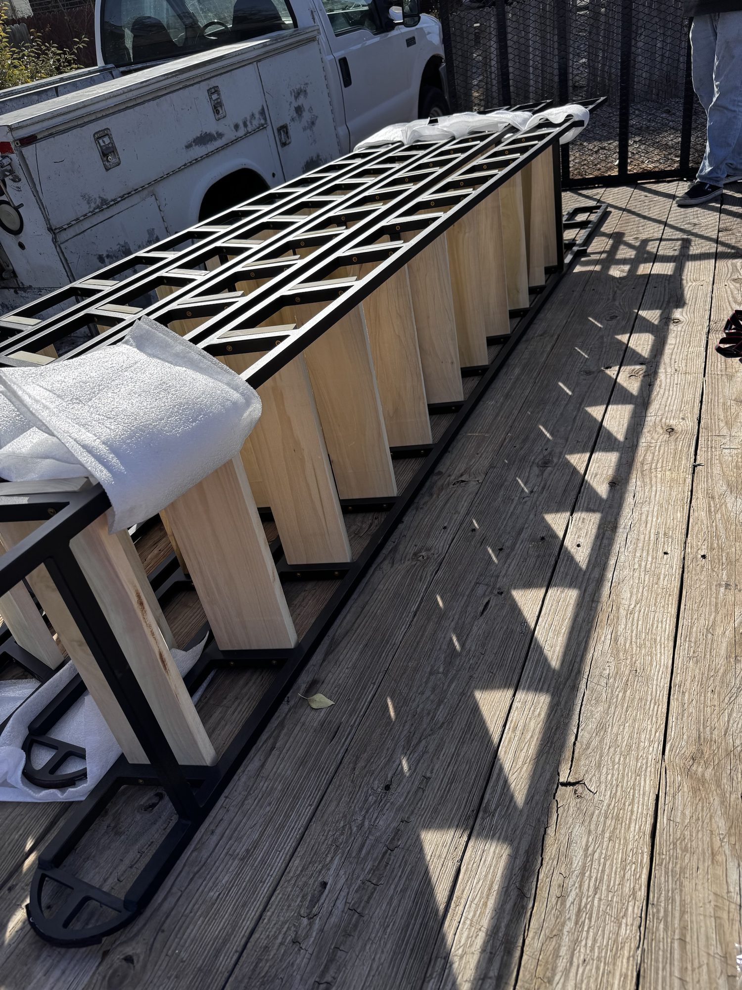 Custom steel loft ladder with timber treads, powder coated black, wrapped for delivery outside the Sandbar Fabrication shop